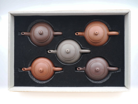 Top-down view of the five anniversary teapots securely nestled in the custom foam-lined collector's box.