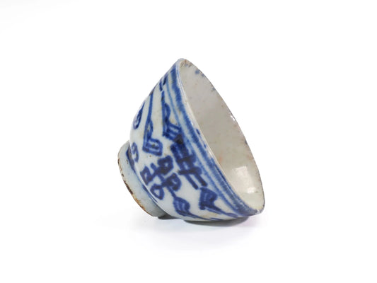 Tilted side view of an antique Mid-Qing Dynasty Double Happiness cup showing the hand-painted blue-and-white Shuangxi pattern and glazed interior