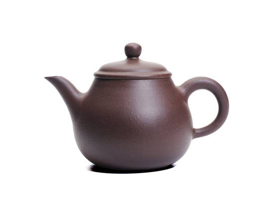 Side view of the Da Ming Yuan Luo Han teapot showing its pear‑shaped bronze‑grade purple clay body, slender spout and round handle.