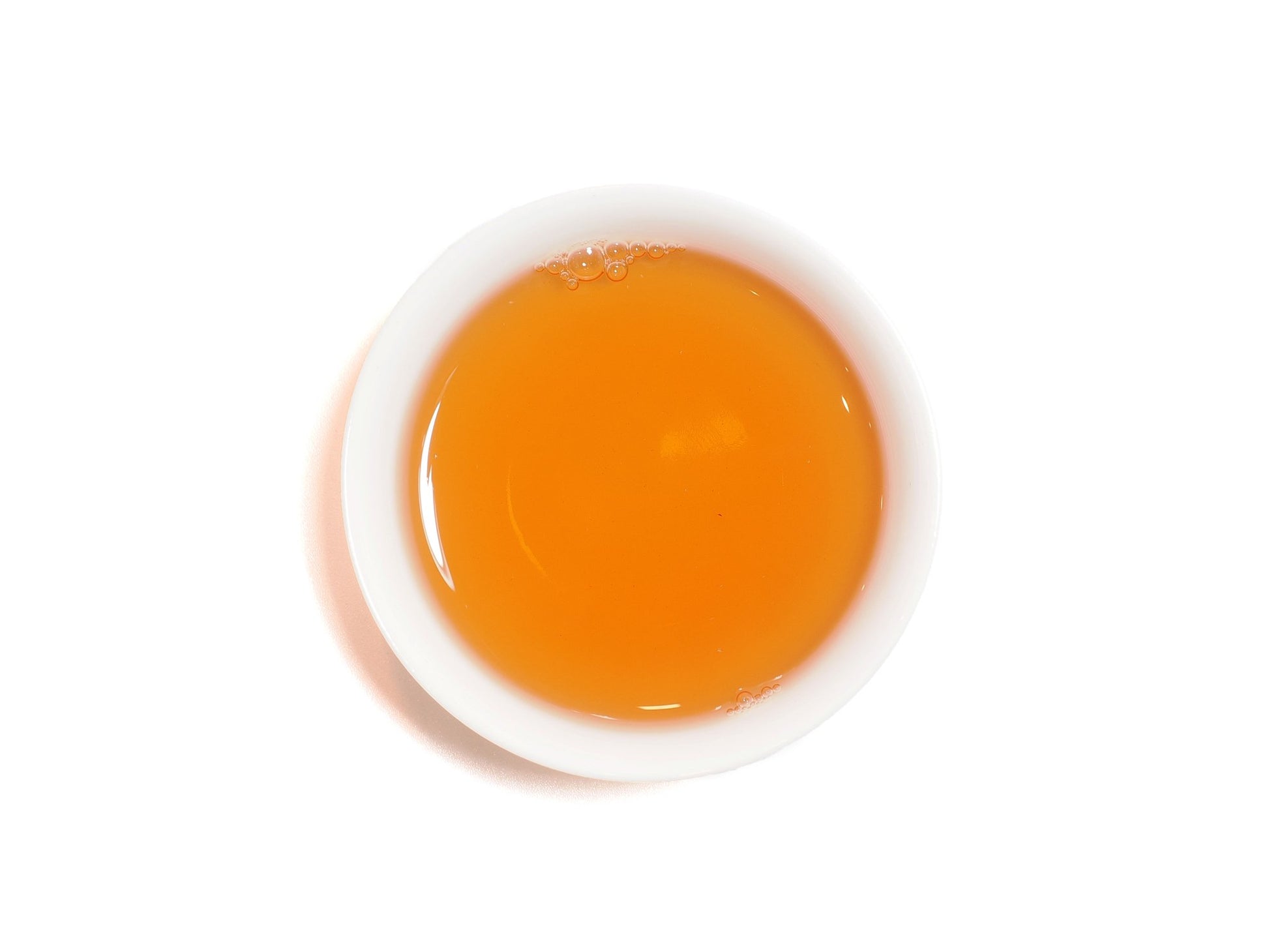 Top view of brewed Fo Shou tea liquor in white porcelain cup