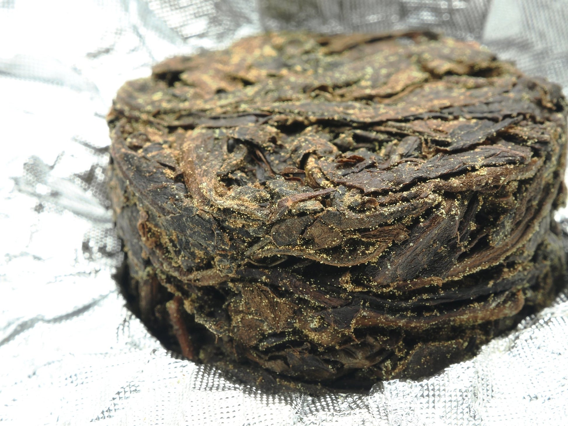 Close-up of Cha Zhi Ji Gao Ma Jin Hua Hei Cha 8g Mini Tuan Cha with visible golden flowers (Eurotium cristatum) on compressed dark tea surface