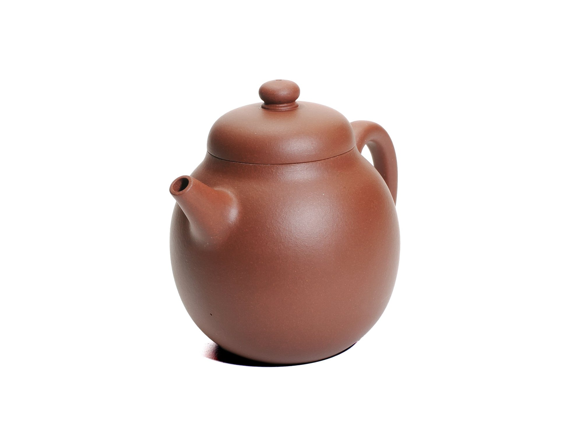 Angled front‑right view of the Ming‑style Da Long Dan teapot displaying its rounded body, short spout and domed lid knob in reddish clay.