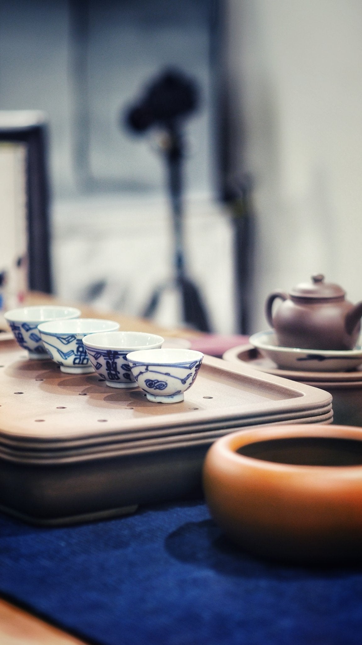 Qing Dynasty blue and white porcelain teacups with Double Happiness motif, arranged on a Gongfu tea tray alongside a Yixing clay teapot