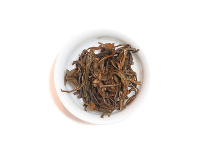 Wet leaves of Yixing Gong Hong black tea after infusion in a white teacup